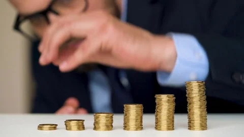 Man stacking gold coins into increasing columns Video stock 77907329
