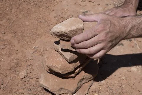 Man stacks rocks in the desert to make a cairn, Arches National Park, Utah Stock Photos