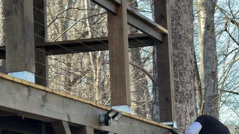 Man staining deck on a ladder 스톡 동영상 332744705