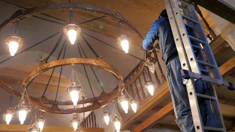 A man on the stairs changes a light bulb in an ancient chandelier in a mosque Stock Footage 202008927