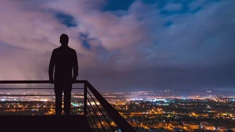 The man stand on the balcony on the background of the night town. Time lapse Stock Footage
