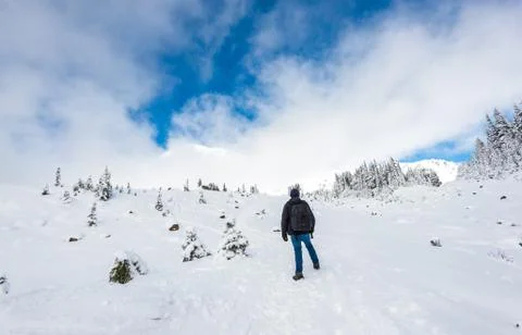 A man stand facing the mountain on a path cover with snow in paradise area,sc Stock Photos