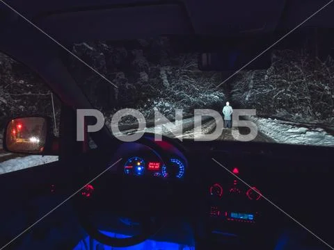 The man stand on the forest road near the car. inside view. evening night tim Stock Photos