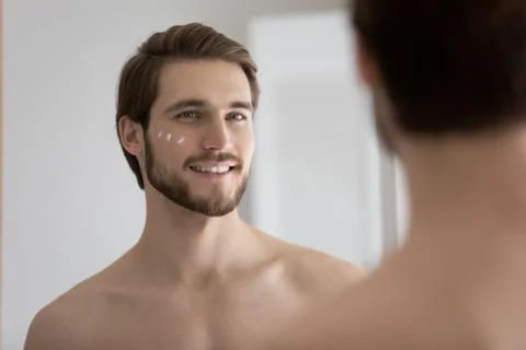 Man stand in front of mirror with applied face cream Stock Photos