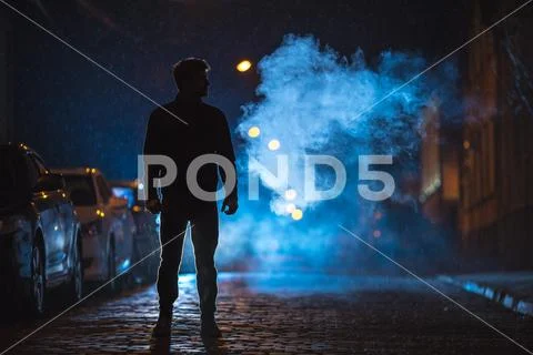 The man stand on the fume street. Evening night time. Telephoto lens shot Stock Photos