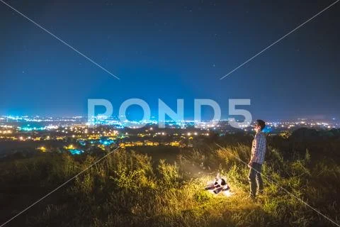 The man stand near the bonfire on the background of the city. night time Stock Photos