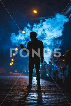 The man stand near the cloud of smoke. Evening night time Stock Photos