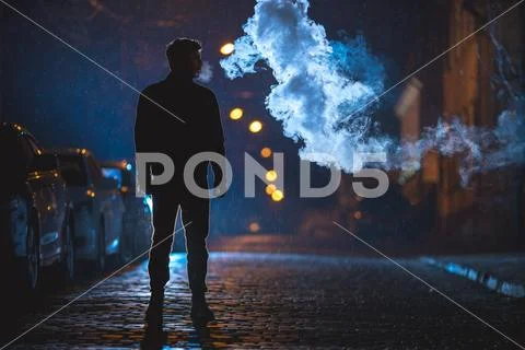 The man stand near the cloud of smoke. Evening night time Stock Photos