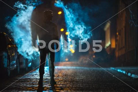 The man stand near the cloud of smoke. Evening night time Stock Photos