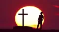The man stand near the cross against the background of sunrise. Real time 4k or 4k+ Resolution