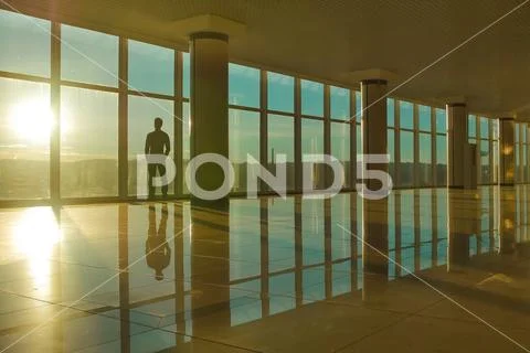 The man stand near the panoramic window on the background of the city Stock Photos