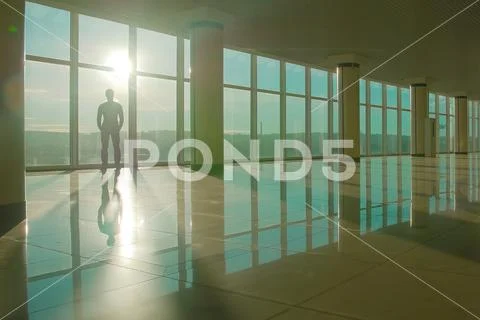 The man stand near the panoramic window on the background of sunrise Stock Photos