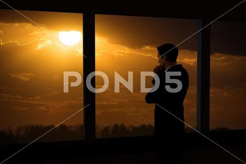 The man stand near the panoramic window against the background of the sun Stock Photos