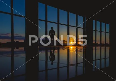 The man stand near the skyscraper window on the background of sunset Stock Photos