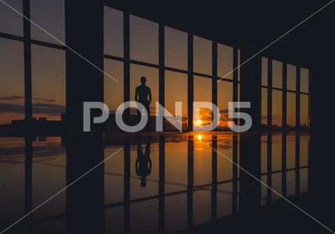 The man stand near skyscraper window on a background of sunset Stock Photos