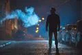 The man stand near the smoke. Evening night time. Telephoto lens shot Photo