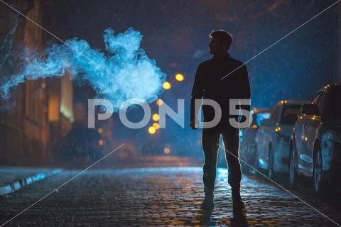 The man stand near the smoke. Evening night time. Telephoto lens shot Stock Photos