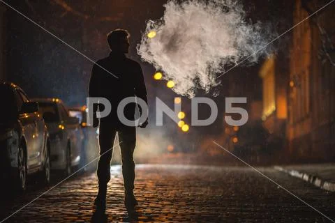 The man stand near the smoke. Evening night time. Telephoto lens shot Stock Photos