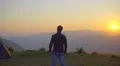The man stand near the tent on the background of the mountain. Real time capture 4k or 4k+ Resolution