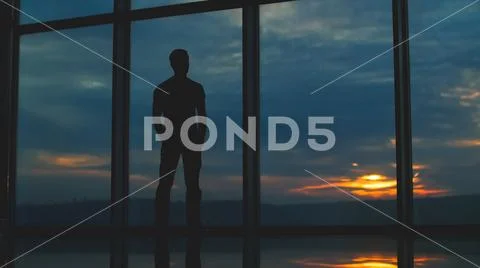 The man stand near the window on the background of clouds Stock Photos