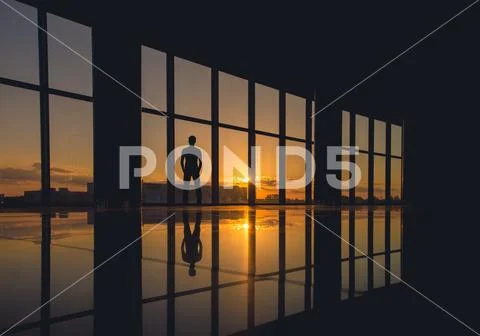 The man stand near the window on a background of sunrise Stock Photos