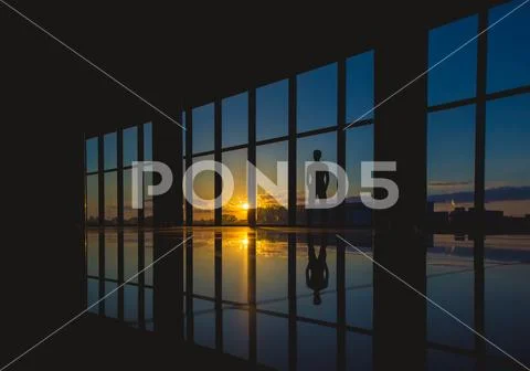 The man stand near the window in skyscraper on the sunset background Stock Photos