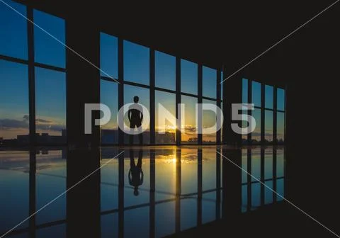The man stand near the window in skyscraper on a sunset background Stock Photos