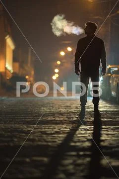 The man stand on the rain road. Evening night time. Telephoto lens shot Stock Photos