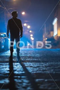 The man stand on the rain road. Evening night time. Telephoto lens shot Stock Photos