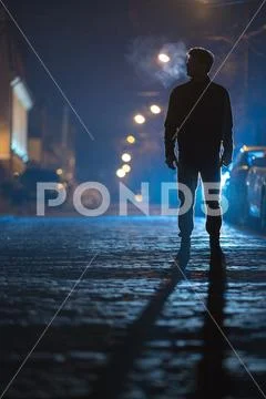 The man stand on the rain road. Evening night time. Telephoto lens shot Stock Photos