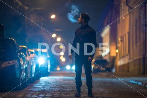 The man stand on the road. Evening night time. Telephoto lens shot Stock Photos