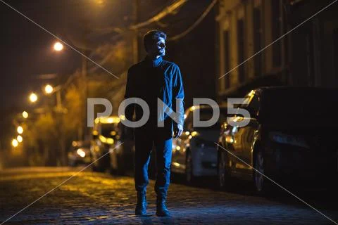 The man stand on the road. Evening night time. Telephoto lens shot Stock Photos