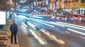 The man stand on the roadside against the background of traffic stream. Eve.. Photo