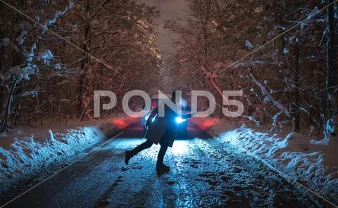 The man stand on the snowy road against the car. evening night time Stock Photos