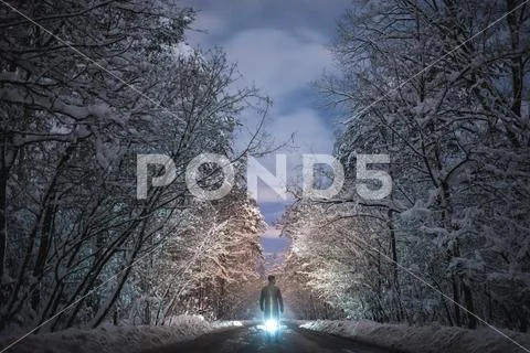 The man stand on a snowy road on a bright light background. evening night time Stock Photos