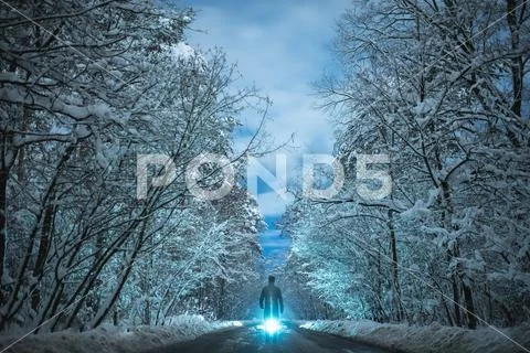 The man stand on a snowy road on a bright light background. evening night tim Stock Photos