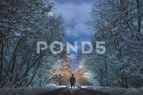 The man stand on a snowy road in the forest. evening night time Stock Photos