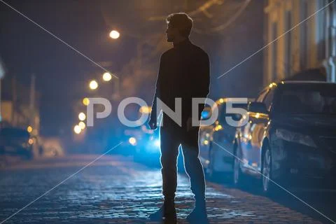 The man stand on the stone road. Evening night time. Telephoto lens shot Stock Photos