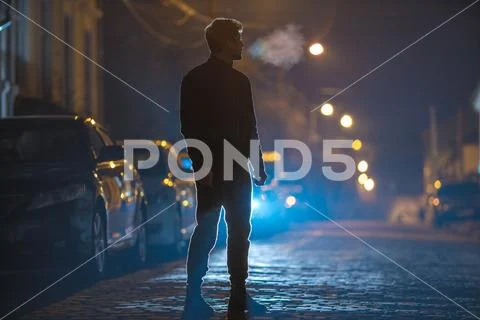 The man stand on the stone road. Evening night time. Telephoto lens shot Stock Photos