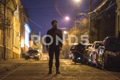 The man stand on the street. Evening night time. Telephoto lens shot Stock Photos