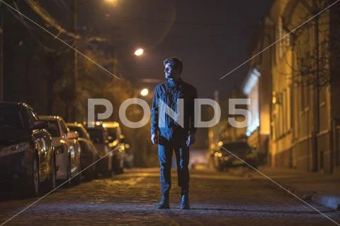The man stand on the street. Evening night time. Telephoto lens shot Stock Photos