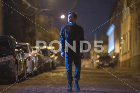The man stand on the street. Evening night time. Telephoto lens shot Stock Photos
