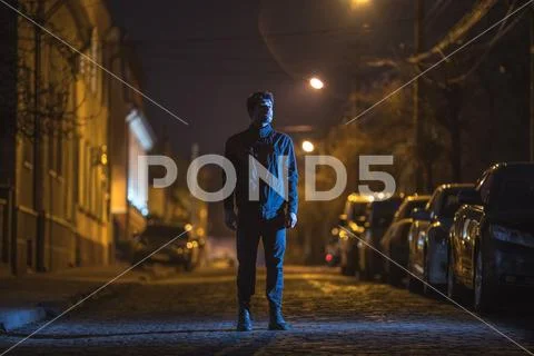 The man stand on the street. Evening night time. Telephoto lens shot Stock Photos