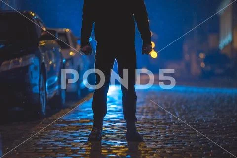 The man stand on the wet road. Evening night time. Telephoto lens shot Stock Photos