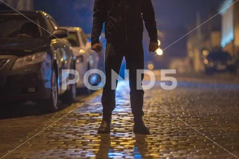 The man stand on the wet road. Evening night time. Telephoto lens shot Stock Photos