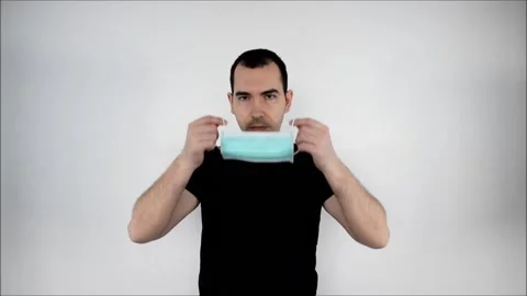 Man stand white background, put on, protect save lifes,  closeup. Coronavirus. Stock Footage 134566944