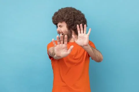Man standing with afraid or worry face, looking at camera and blocking with his Foto stock