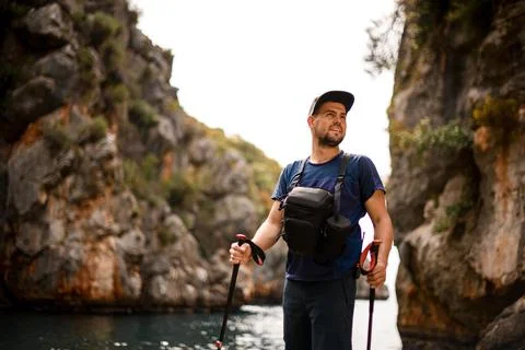 Man standing against the backdrop of cliffs and sky and looks away Photos