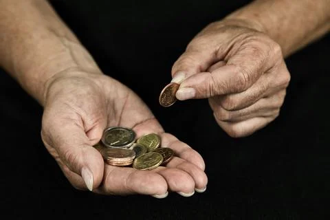 Man standing against a solid black background, holding money coins as a symbol o 写真素材