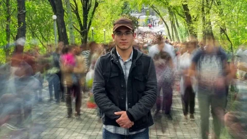 Man standing alone in blurred crowd, on background green trees. Time Lapse Stock Footage 80095009